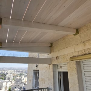 פרגולת עץ מותקנת במרפסת דירה בבניין מגורים