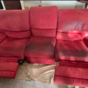 ספה אדומה עם כתמים כהים ומגבת על הרצפה