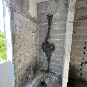 קיר בלוקים עם צנרת חשופה ותיקוני טיח