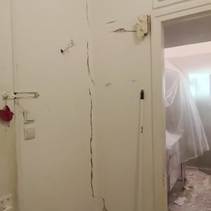 קיר עם סדקים ותיקונים, מטאטא על הרצפה