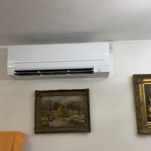 מזגן מותקן על קיר עם תמונות ממוסגרות