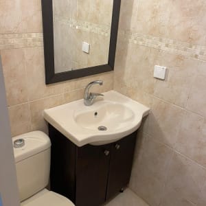 כיור אמבטיה עם ברז ומראה על הקיר