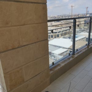 מרפסת עם קיר אבן, מעקה זכוכית ושני עציצים קטנים