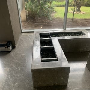 אדנית אבן עם צמחים קטנים ליד חלון זכוכית