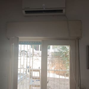 מזגן מותקן מעל דלת זכוכית עם סורגים