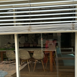 תריסים לבנים פתוחים למחצה על חלון זכוכית