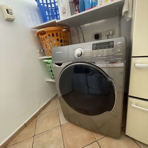 מכונת כביסה עם סלסלות ומוצרי ניקוי על מדף