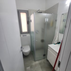 מקלחון זכוכית בחדר אמבטיה מודרני עם כיור ומראה