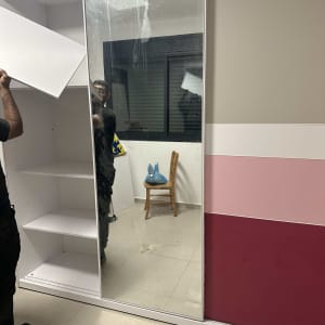 אדם מתקין מדף בארון עם דלת מראה