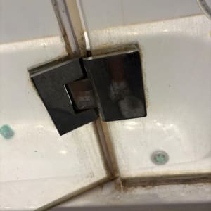 ציר דלת זכוכית במקלחת עם סימני חלודה