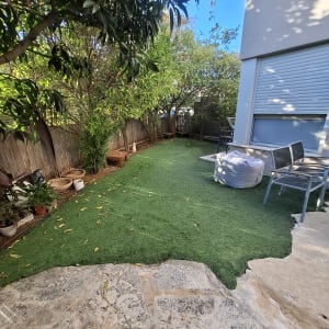 גינה עם דשא מלאכותי ועצים מסביב