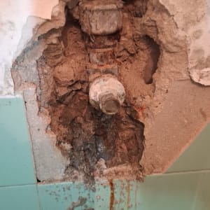 צינור חשוף בקיר עם טיח מתפורר