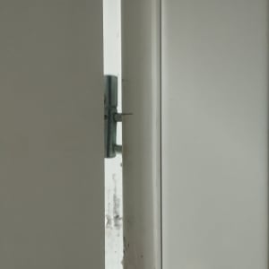 דלת לבנה פתוחה חלקית עם מנעול בריח