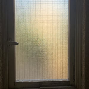 חלון זכוכית עם רשת מתכת במסגרת עץ