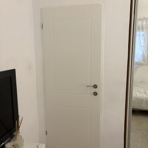 דלת לבנה בחדר עם טלוויזיה ונר