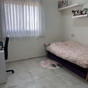 וילון לבן תלוי בחדר שינה עם מיטה ושולחן כתיבה