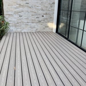 דק עץ בהיר ליד קיר לבנים וחלון זכוכית