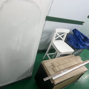 כיסא לבן, תיק כחול, לוח עץ ופס מתכת על רצפה ירוקה