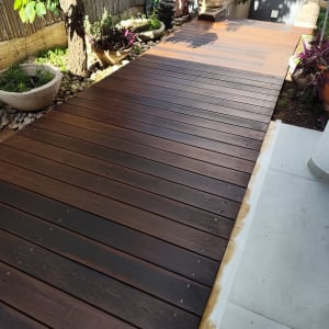 דק עץ בגינה עם עציצים ואופניים ברקע