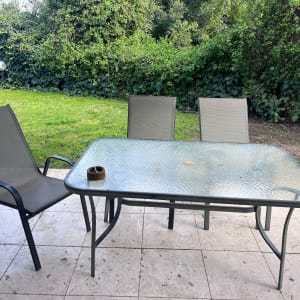 שולחן זכוכית עם כיסאות בגינה ירוקה