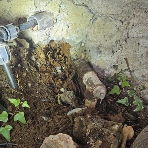 צינור מים ישן עם חלודה ודליפה בקיר בטון