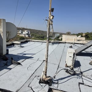 גג עם אנטנות וכבלים, נוף עירוני ברקע