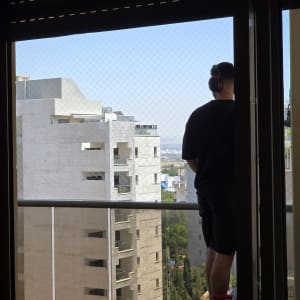 אדם עומד ליד חלון עם רשת בטיחות