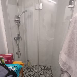 מקלחון זכוכית עם ראש מקלחת ומגבת תלויה