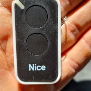 שלט רחוק לשער חשמלי מתוצרת Nice מוחזק בכף יד