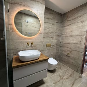 שיפוץ חדר אמבטיה עם כיור חדש ומראה עגולה מוארת