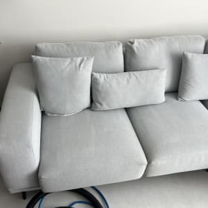 ספה אפורה עם כריות וצינור ניקוי על הרצפה