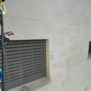 אדם בעבודות גובה ליד חלון עם תריסים