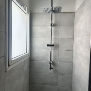 מקלחת עם אריחים אפורים וראש מקלחת מרובע