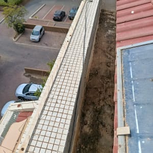 גג עם רעפים אדומים ומעקה עם רשת מתכת