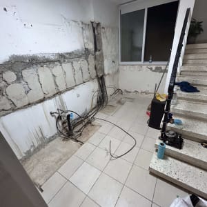 שיפוץ קיר עם חוטי חשמל חשופים ורצפה מרוצפת