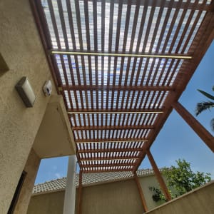 פרגולה מעץ בחצר בית עם שמיים כחולים