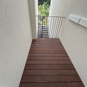 מרפסת עץ עם מעקה ברזל וגינה ברקע