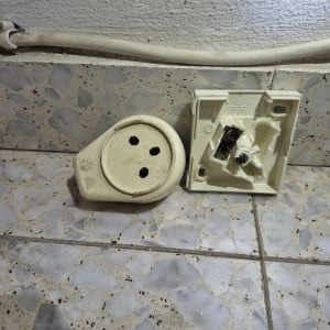 שקע חשמלי מפורק על רצפה מרוצפת