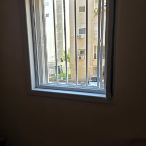 סורגים ישרים לבנים ממתכת המותקנים בחלון בית