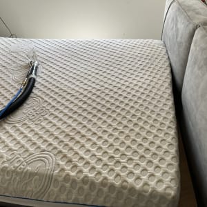 צינור ניקוי על מזרן ליד ספה אפורה