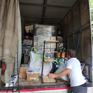 אדם מעמיס חפצים למשאית הובלה פתוחה