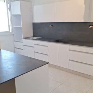 מטבח עם משטחי עבודה כהים וארונות לבנים