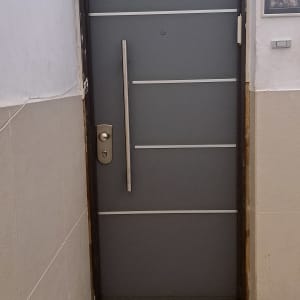 דלת אפורה עם ידית מתכת אנכית ופסי קישוט אופקיים