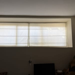 זוג וילונות רומאים בהירים להצללה מותקנים בחלון רחב