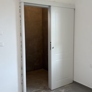 דלת הזזה לבנה בחדר עם רצפת אריחים אפורה