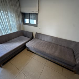 שתי ספות אפורות בחדר עם וילונות וחלון