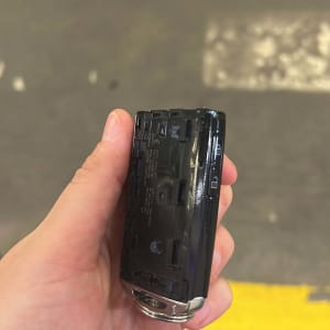 מפתח רכב מוחזק ביד על רקע רצפה אפורה