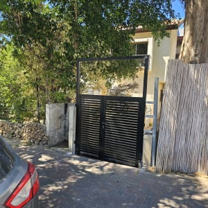 שער מתכת שחור ליד בית ועצים