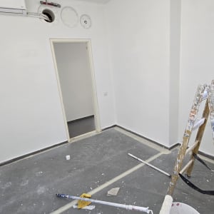 חדר צבוע בלבן עם סולם, דלי ורולר צביעה