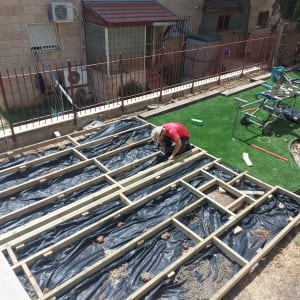 אדם עובד על מסגרת עץ בגינה